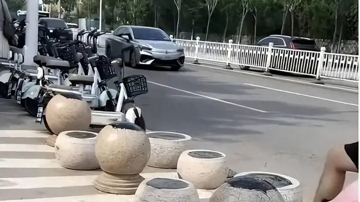 日照一海水浴场门口隔离石墩被涂抹沥青，游客带娃经过鞋和身上都粘上